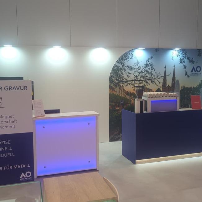 Live-Laser-Station von LASERPIX mit Faserlaser f&uuml;r Metall im Corporate Design von American Orthodontics neben der Barista-Bar